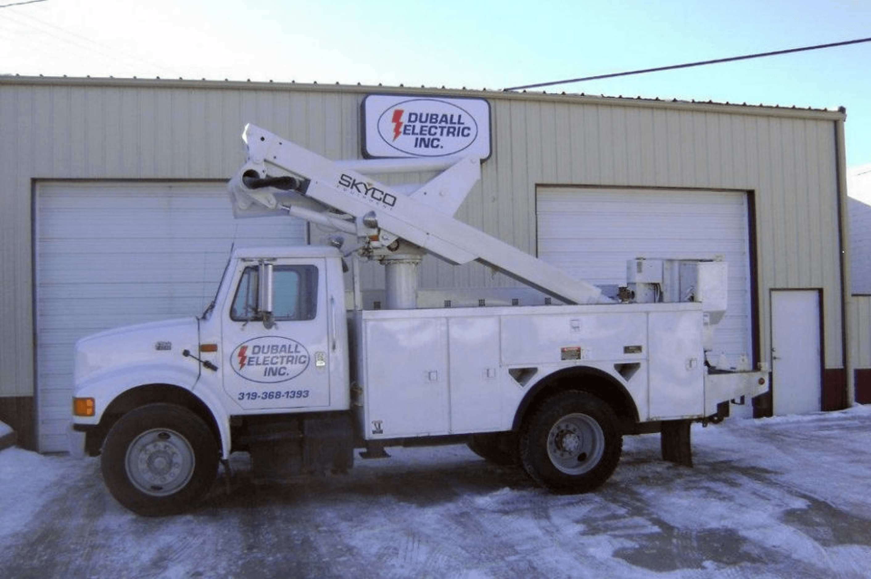 Picture of a Duball Electric boomtruck, and building.